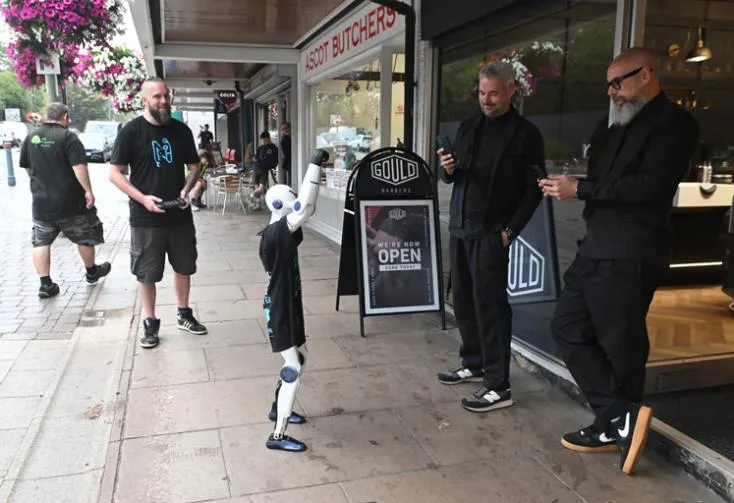 Jimmy with both arms raised outside Gould Barbers on Ascot High Street, with people stopping to look